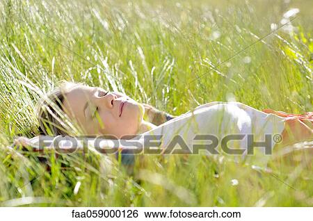 Young woman napping in tall grass View Large Photo Image Stock Photograph - Young woman napping in tall grass. Fotosearch