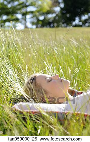 Stock Photography - Young woman napping in tall grass. Fotosearch