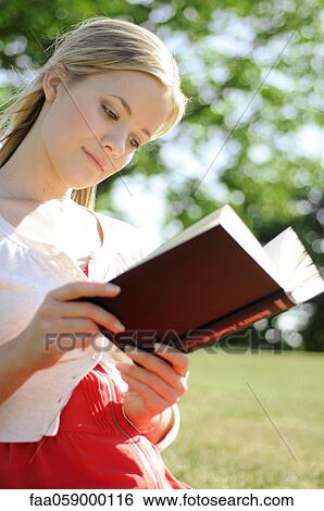 Young woman reading book outdoors View Large Photo Image Stock Photograph - Young woman reading book outdoors. Fotosearch