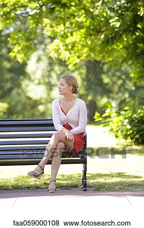 Young woman sitting on park bench View Large Photo Image Stock Photo - Young woman sitting on park bench. Fotosearch