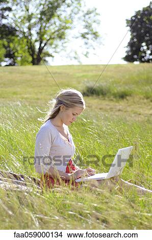 Young woman using laptop computer in park View Large Photo Image Picture - Young woman using laptop computer in park. Fotosearch
