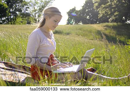 Young woman using laptop computer in park View Large Photo Image Stock Image - Young woman using laptop computer in park. Fotosearch