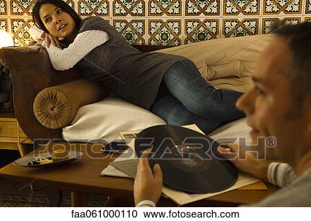Couple relaxing in living room, man holding record View Large Photo Image Stock Image - Couple relaxing in living room, man holding record. Fotosearch