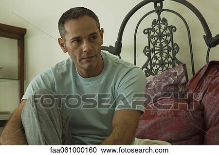 Man sitting on bed, looking away in thought, portrait View Large Photo Image Stock Image - Man sitting on bed, looking away in thought, portrait. Fotosearch
