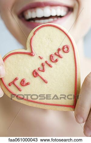 Woman holding up heart-shaped cookie, smiling, cropped View Large Photo Image Stock Image - Woman holding up heart-shaped cookie, smiling, cropped. Fotosearch