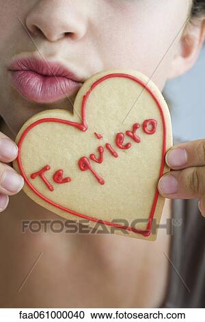 Woman puckering lips, holding heart-shaped cookie View Large Photo Image Stock Image - Woman puckering lips, holding heart-shaped cookie. Fotosearch