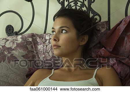 Young woman in bed, looking away in thought, portrait View Large Photo Image Picture - Young woman in bed, looking away in thought, portrait. Fotosearch