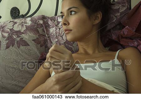 Young woman in bed, looking away in thought, portrait View Large Photo Image Stock Image - Young woman in bed, looking away in thought, portrait. Fotosearch