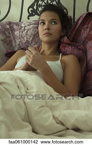 Young woman resting on bed, portrait View Large Photo Image Stock Image - Young woman resting on bed, portrait. Fotosearch