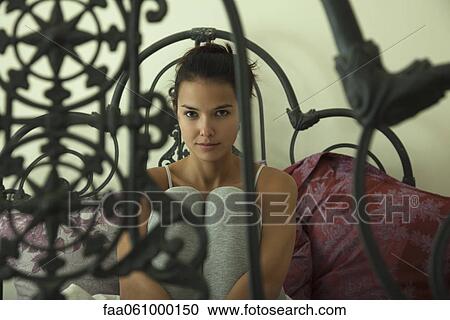 Young woman sitting on bed, portrait View Large Photo Image Stock Image - Young woman sitting on bed, portrait. Fotosearch