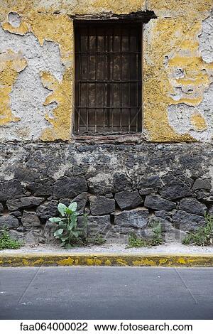 Stock Image - Barred window on dilapidated building exterior. Fotosearch