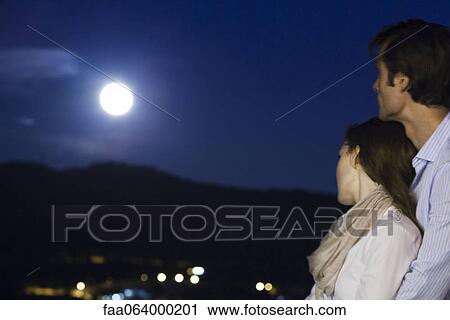 Couple embracing at night, looking at moon View Large Photo Image Stock Image - Couple embracing at night, looking at moon. Fotosearch
