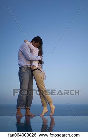 Couple embracing on edge of infinity pool at dusk View Large Photo Image Stock Photograph - Couple embracing on edge of infinity pool at dusk. Fotosearch