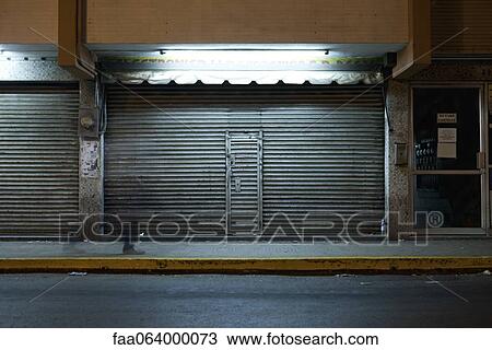 Store front with locked roll-up door at night View Large Photo Image Stock Image - Store front with locked roll-up door at night. Fotosearch