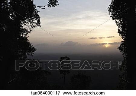 Sun setting over tropical rainforest View Large Photo Image Stock Photo - Sun setting over tropical rainforest. Fotosearch