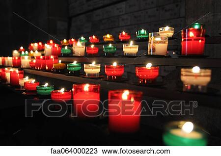 Stock Image - Votive candles burning in church. Fotosearch