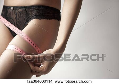 Woman measuring her thigh with measuring tape View Large Photo Image Picture - Woman measuring her thigh with measuring tape. Fotosearch