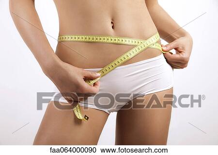Young woman measuring hips with measuring tape, cropped View Large Photo Image Stock Image - Young woman measuring hips with measuring tape, cropped. Fotosearch