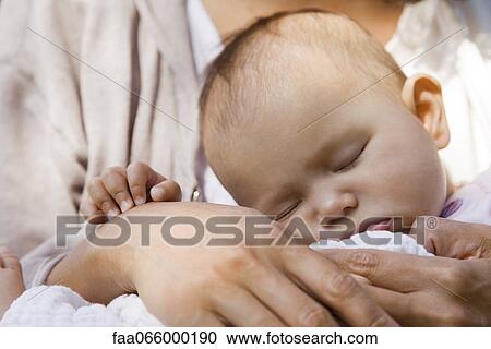 Stock Image - Baby sleeping in parent's arms. Fotosearch
