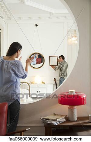 Couple hanging framed art in home View Large Photo Image Stock Photo - Couple hanging framed art in home. Fotosearch