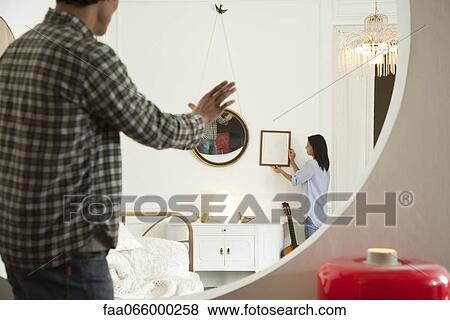 Couple hanging framed art in home View Large Photo Image Stock Photo - Couple hanging framed art in home. Fotosearch