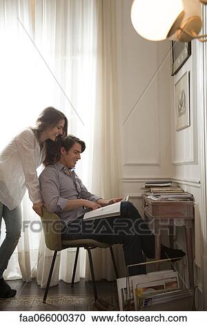 Couple looking at magazine together View Large Photo Image Stock Image - Couple looking at magazine together. Fotosearch
