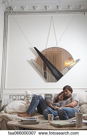 Couple relaxing together, looking at digital tablet View Large Photo Image Stock Photo - Couple relaxing together, looking at digital tablet. Fotosearch