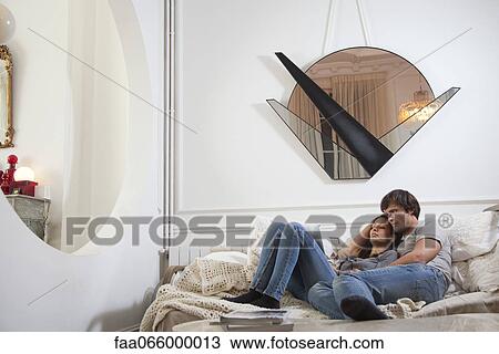 Couple relaxing together on bed, looking at digital tablet View Large Photo Image Stock Image - Couple relaxing together on bed, looking at digital tablet. Fotosearch