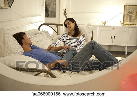 Couple relaxing together on bed View Large Photo Image Stock Photograph - Couple relaxing together on bed. Fotosearch