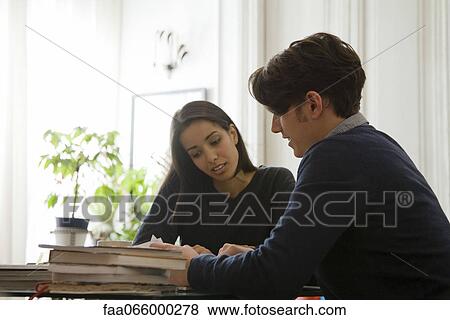 Couple sitting at table reading together View Large Photo Image Stock Photo - Couple sitting at table reading together. Fotosearch