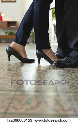 Stock Image - Couple standing face to face, cropped view of feet. Fotosearch