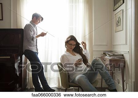 Couple text messaging at home View Large Photo Image Stock Photograph - Couple text messaging at home. Fotosearch