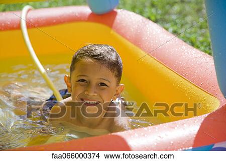 Little boy playing in wading pool, portrait View Large Photo Image Picture - Little boy playing in wading pool, portrait. Fotosearch
