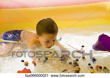Stock Image - Little boy playing with toys in wading pool. Fotosearch