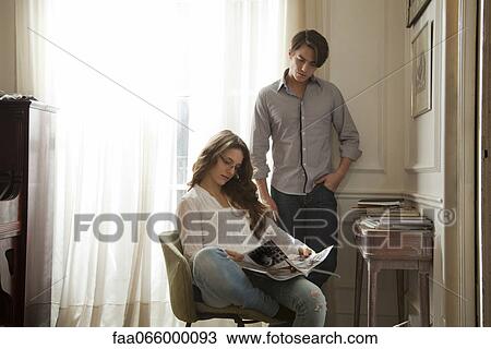 Man looking over woman's shoulder as she reads magazine View Large Photo Image Stock Image - Man looking over woman's shoulder as she reads magazine. Fotosearch