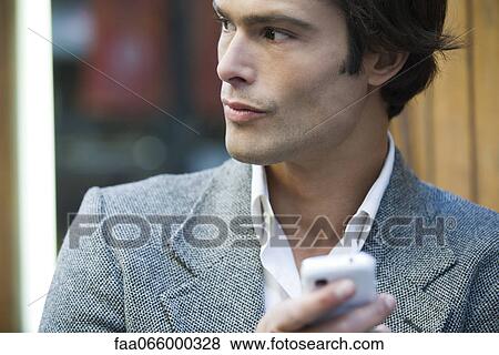 Man outdoors, holding cell phone View Large Photo Image Stock Photo - Man outdoors, holding cell phone. Fotosearch