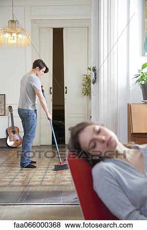 Man sweeping floor at home, woman napping in foreground View Large Photo Image Stock Photo - Man sweeping floor at home, woman napping in foreground. Fotosearch