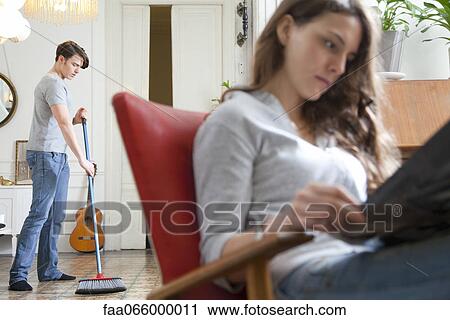 Man sweeping floor while wife reads View Large Photo Image Stock Image - Man sweeping floor while wife reads. Fotosearch