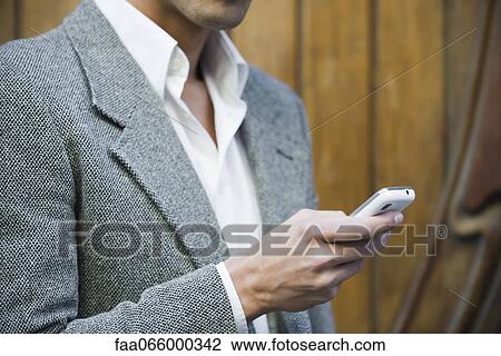Stock Image - Man text messaging outdoors, cropped. Fotosearch