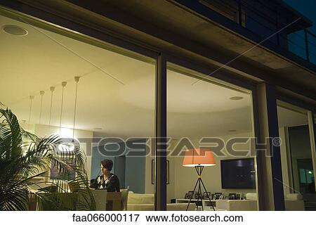 Man using laptop in living room, viewed through window View Large Photo Image Stock Photo - Man using laptop in living room, viewed through window. Fotosearch