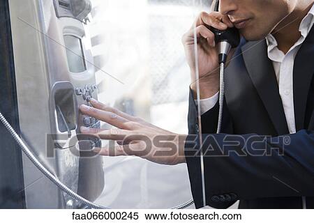 Stock Photography - Man using pay phone. Fotosearch