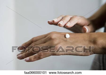 Stock Image - Woman moisturizing hands, cropped. Fotosearch
