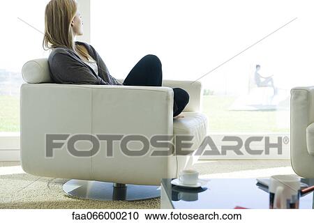 Woman relaxing in armchair, gazing out window View Large Photo Image Stock Image - Woman relaxing in armchair, gazing out window. Fotosearch
