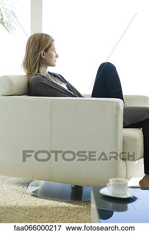 Woman relaxing in armchair, looking out window View Large Photo Image Stock Photo - Woman relaxing in armchair, looking out window. Fotosearch