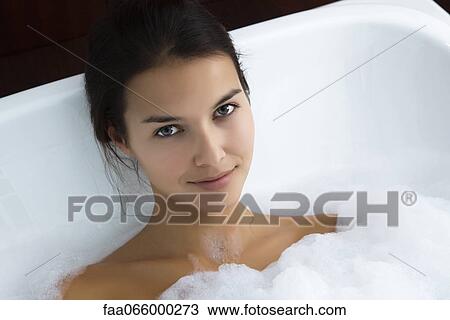 Stock Image - Woman relaxing in bubble bath, portrait. Fotosearch