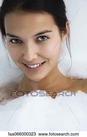 Stock Image - Woman relaxing in bubble bath, portrait. Fotosearch