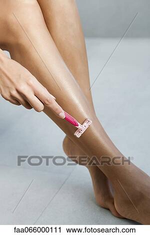 Stock Image - Woman shaving legs, cropped. Fotosearch