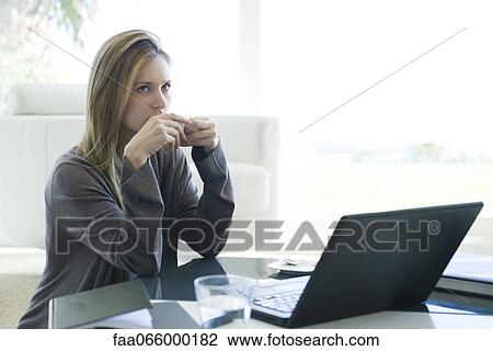 Woman sitting at coffee table with laptop computer, drinking coffee View Large Photo Image Stock Image - Woman sitting at coffee table with laptop computer, drinking coffee. Fotosearch