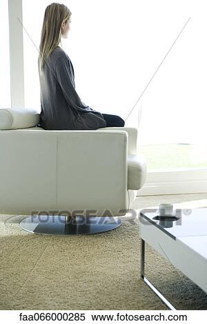 Woman sitting on armchair, gazing out window View Large Photo Image Stock Photography - Woman sitting on armchair, gazing out window. Fotosearch