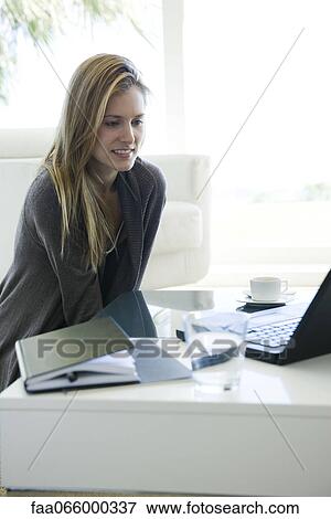 Woman using laptop computer at coffee table View Large Photo Image Stock Photo - Woman using laptop computer at coffee table. Fotosearch
